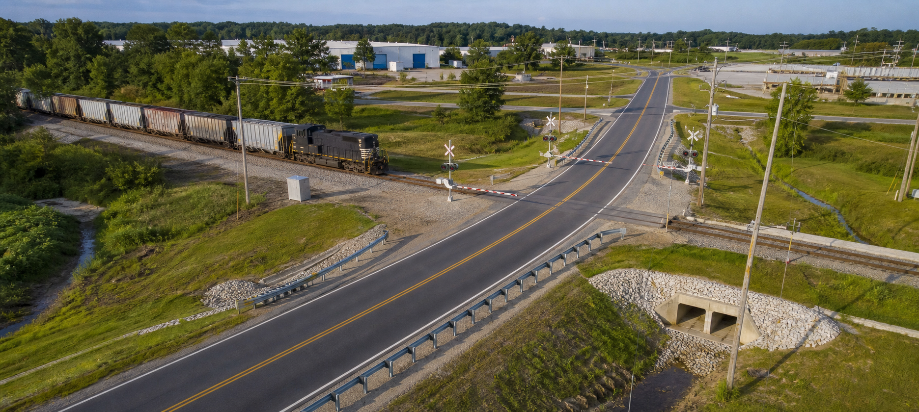 Roadway and freight railroad crossing with coordinated drainage and utility infrastructure